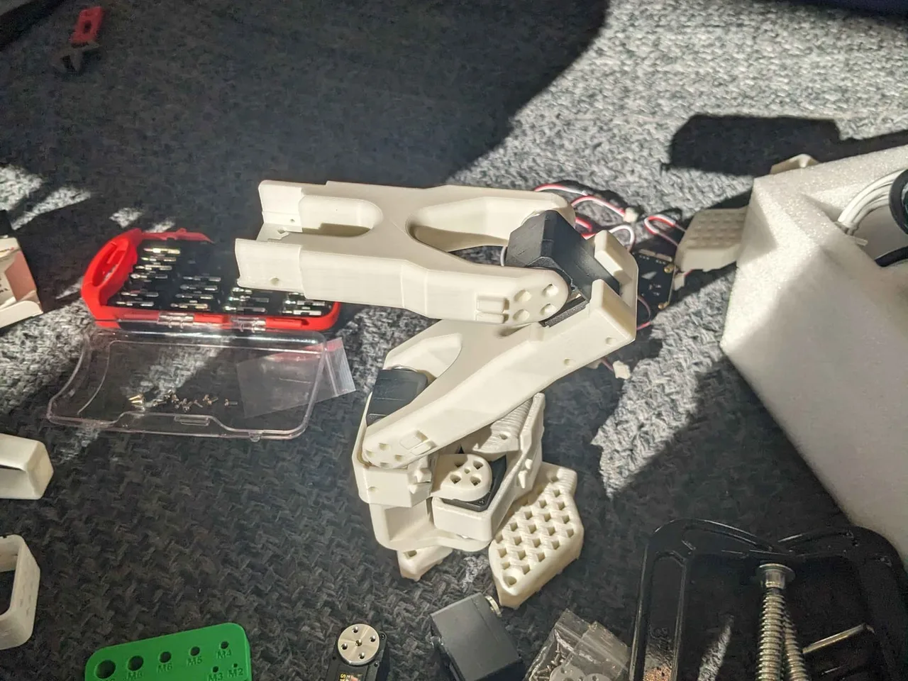 A half-built arm on the carpet next to the screwdriver kit