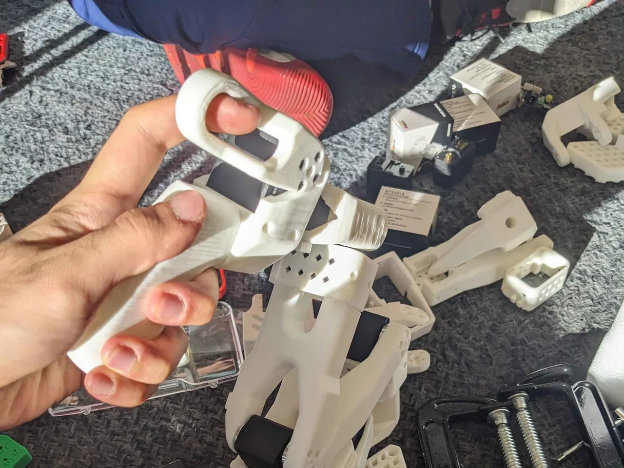 A half-assembled arm held in hand, with servos fitted into the printed links