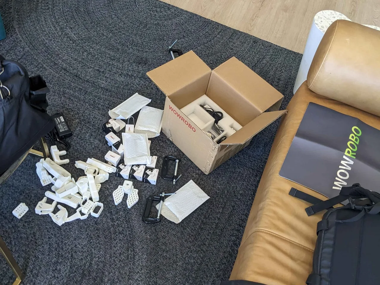 The SO-101 kit unboxed on the floor, printed parts spilling out of the box