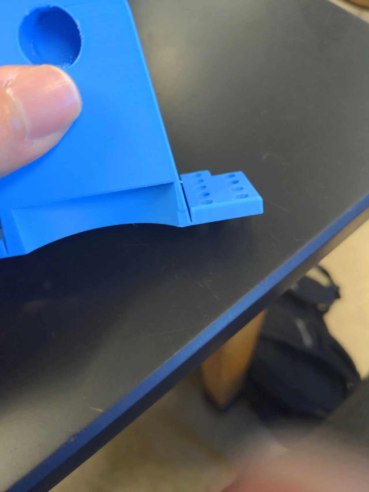 A blue printed housing with a visible separation line where its mounting bracket meets the body