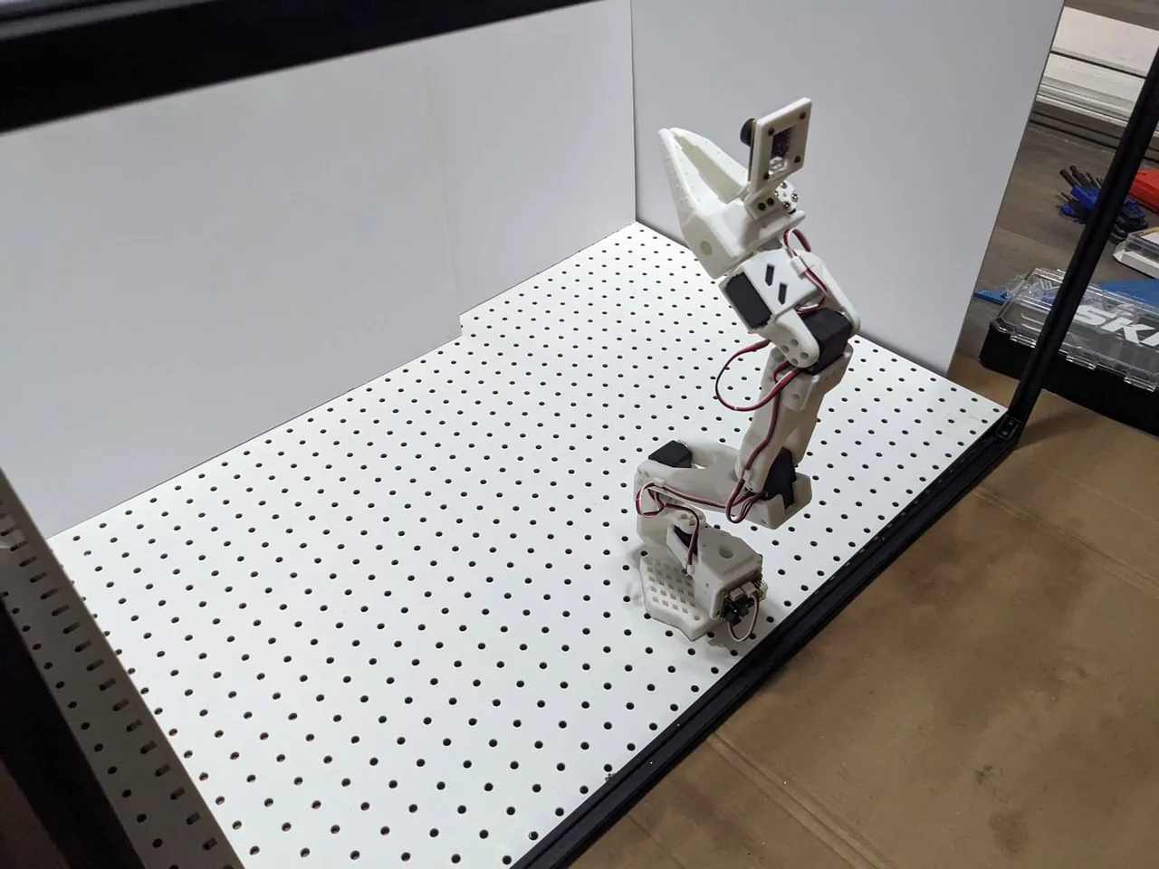 The follower arm standing on the pegboard deck inside the white enclosure